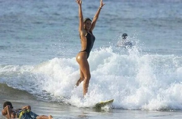 Le surf, le bon plan pour voir les filles en bikini - une femmme sexy debout sur son surf les bras en l air apparemment contente d avoir reussi a faire du surf